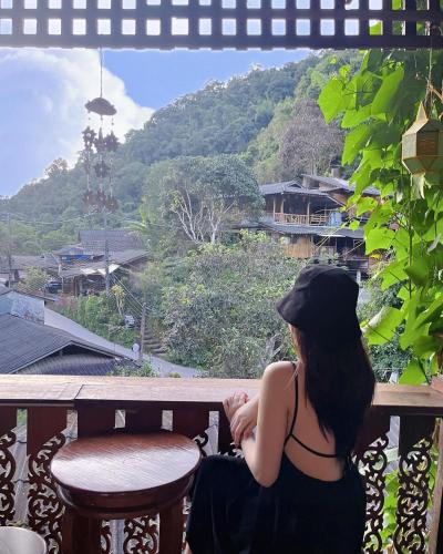 a woman sitting on a balcony looking out at the mountains at Preanhuan Homestay in Mae On