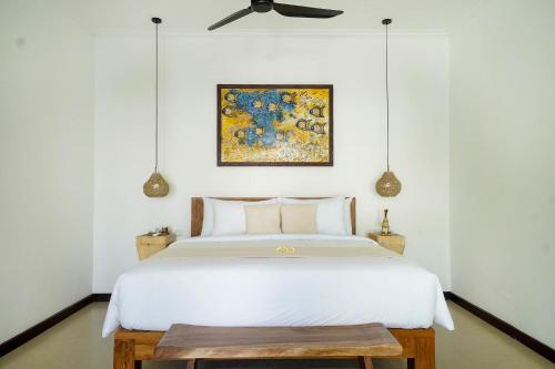 a bedroom with a white bed and a painting on the wall at SunGlow Villa in Seminyak
