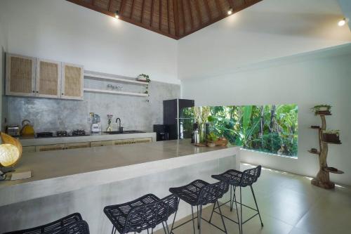 a kitchen with black chairs and a counter top at SunGlow Villa in Seminyak