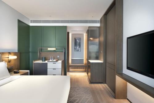 a hotel room with a bed and a flat screen tv at The Barony Jinan East in Jinan