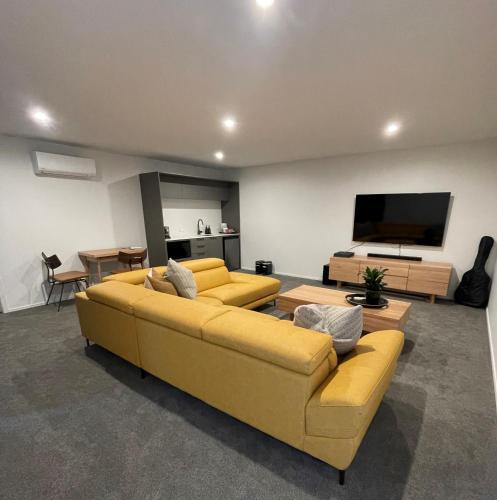sala de estar con sofá amarillo y TV de pantalla plana en Luxury at the Lake, en Hamilton
