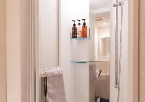 a bathroom with a refrigerator with two bottles of alcohol at COCOSHUKU Nakano in Tokyo