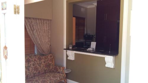 una camera d'albergo con sedia e specchio di Liza's Cottage Guesthouse a Pretoria
