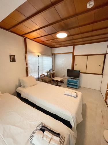 a room with two beds and a table with a television at Kikusui Ryokan in Tamano
