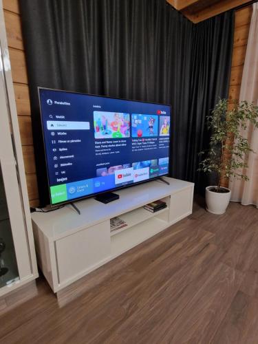 a large flat screen tv sitting on a white cabinet at Baložu rezidence in Jūrmala