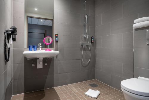 een badkamer met een douche, een wastafel en een toilet bij the niu Timber in Esslingen