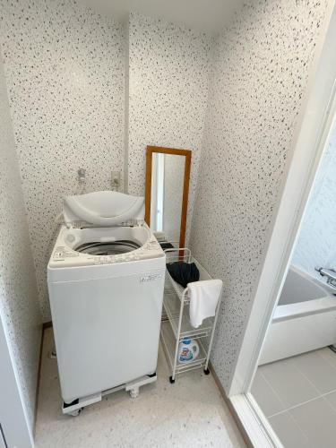 a washing machine in a laundry room with a mirror at Kikusui Ryokan in Tamano