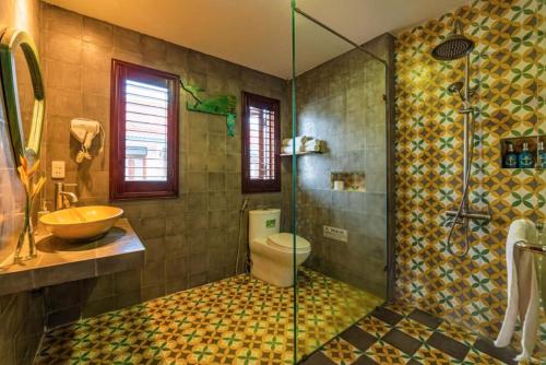 uma casa de banho com um chuveiro, um WC e um lavatório. em Fuse Beachside Hoi An em Hoi An