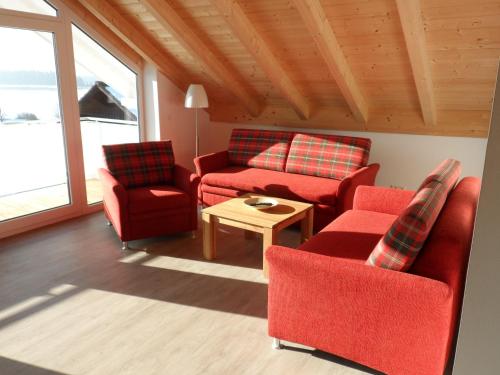 ein Wohnzimmer mit roten Stühlen und einem Tisch in der Unterkunft Ferienwohnungen Hopfensee in Füssen