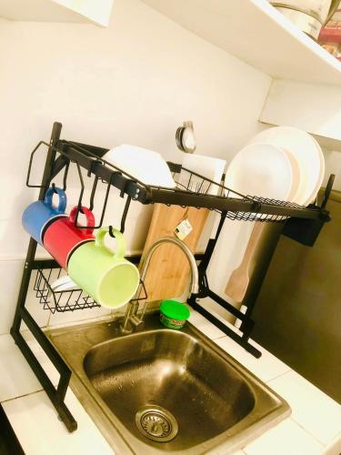 a kitchen sink with plates and pans on a shelf at Avida Tower Sucat, comfortable studio type in Manila