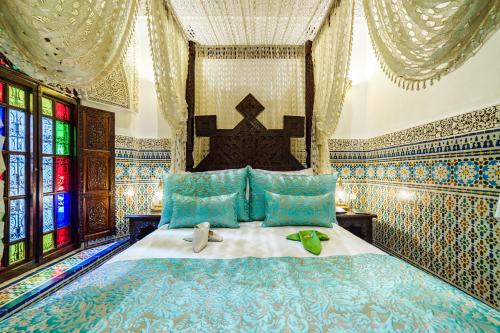 a bedroom with a bed with blue pillows and windows at Riad Rcif & Spa Originale in Fès