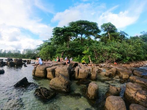 un gruppo di persone sedute sulle rocce nell'acqua di Golden Lotus Homestay a Phu Quoc