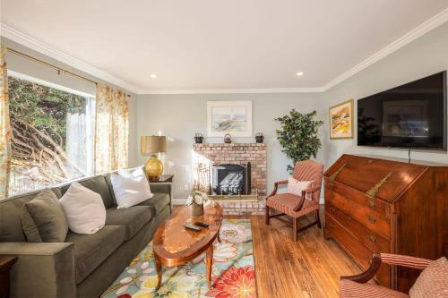 a living room with a couch and a fireplace at Charming Garden Cottage- steps to historic Old Town Half Moon Bay in Half Moon Bay