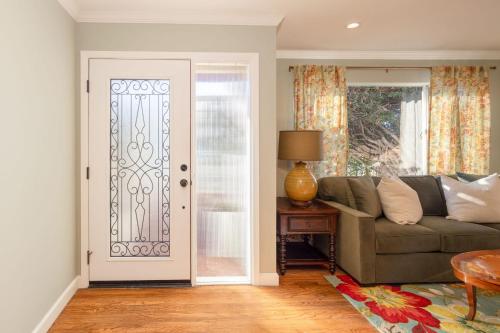 a living room with a couch and a glass door at Charming Garden Cottage- steps to historic Old Town Half Moon Bay in Half Moon Bay