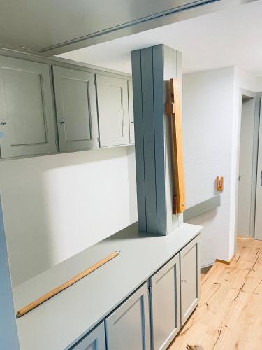 uma cozinha com armários brancos e uma porta azul em Ferienhaus Granula em Linthal