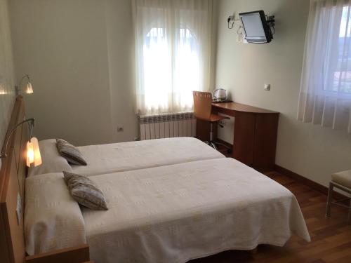 a bedroom with a bed and a desk and a television at Complexo Alameda in Viveiro