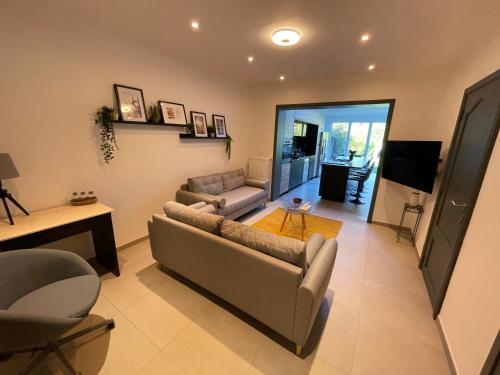 a living room with two couches and a television at LFA Petit coin de verdure au centre in Ans