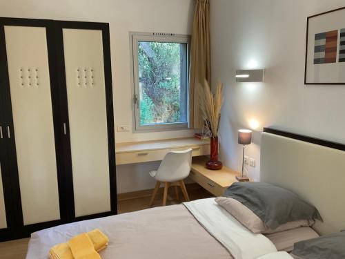 une chambre avec un lit, un bureau et une fenêtre dans l'établissement Residence Cala Sultana -Baie Santa Giulia - rez jardin 1ere ligne, à Porto-Vecchio