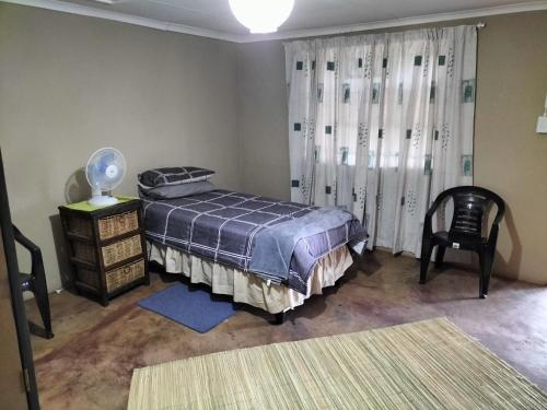 Un dormitorio con una cama y una silla y una ventana. en BLESSINGS Sleep Over, en Mokopane