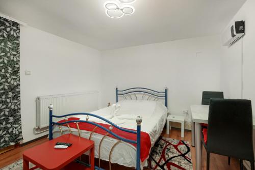 1 dormitorio con 1 cama con mesa roja y escritorio en Stone Gate Apartment #3, en Bucarest