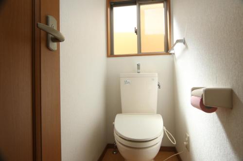 a small bathroom with a toilet with a window at プチバスケット in Chiba