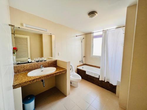 a bathroom with a sink and a toilet and a tub at The Coast Hotel Vung Tau in Vung Tau