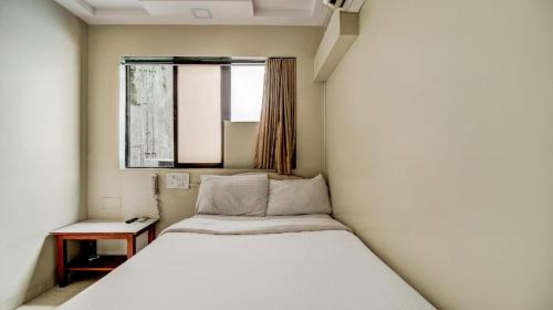 a white bed in a small room with a window at Hotel Raj Inn in Navi Mumbai