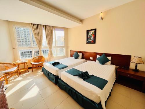 a hotel room with two beds and a table and chairs at The Coast Hotel Vung Tau in Vung Tau
