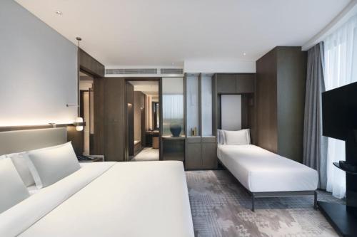a hotel room with two beds and a television at The Barony Jinan East in Jinan