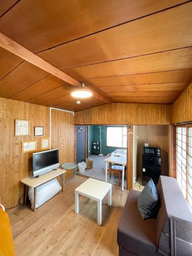 a living room with a couch and a tv at Kikusui Ryokan in Tamano