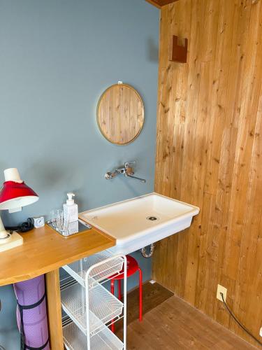 a bathroom with a sink and a wooden wall at Kikusui Ryokan in Tamano
