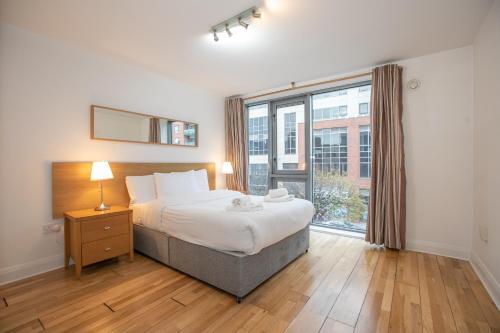 sypialnia z łóżkiem i dużym oknem w obiekcie Parnell Corner Apartments w Dublinie