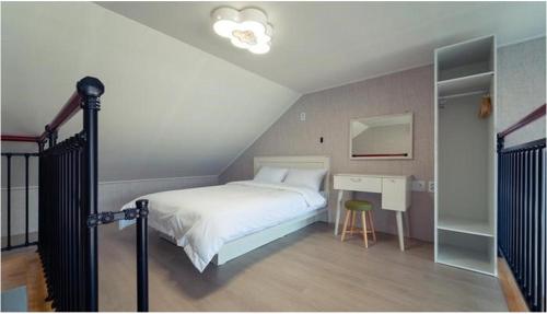 Dormitorio con cama y escritorio en el ático en Seolli Resort Pension, en Namhae