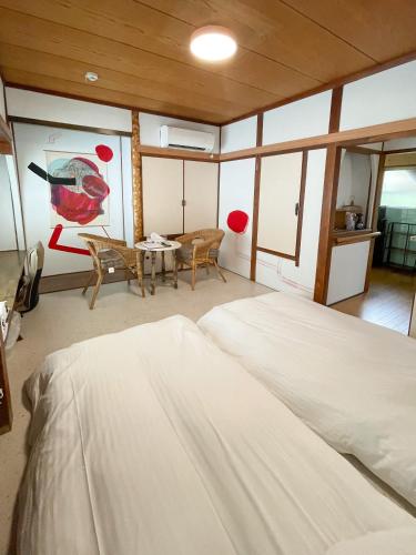 a bedroom with a large bed and a dining room at Kikusui Ryokan in Tamano