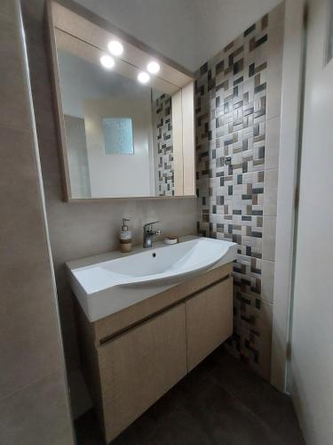 a bathroom with a white sink and a mirror at Aqua Apartments in Loutra Oraias Elenis