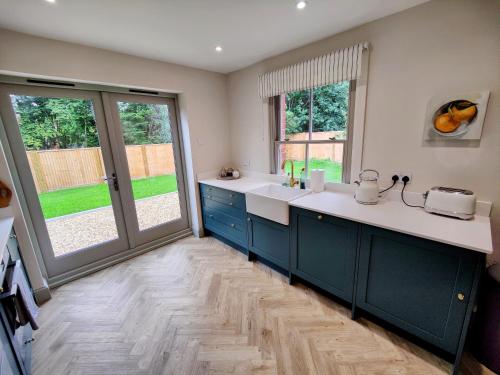 a kitchen with blue cabinets and a sink and windows at Stunning New Forest Cottage close to Paultons Park in Ower