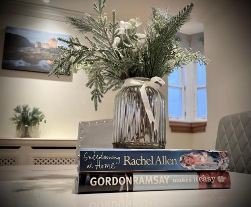 a vase with flowers on top of books on a table at Lomond Castle Penthouse in Luss