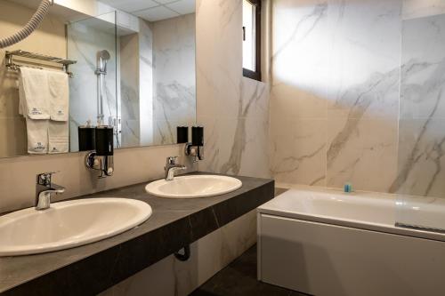 a bathroom with two sinks and a mirror and a tub at Grand Hotel Velingrad in Velingrad