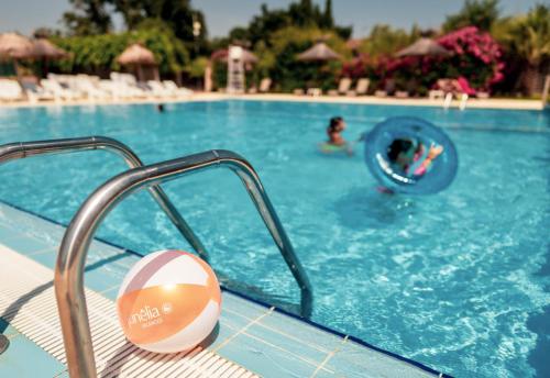 une personne dans une piscine avec un ballon à l'eau dans l'établissement Camping Sunelia L'Argentière, à Cogolin