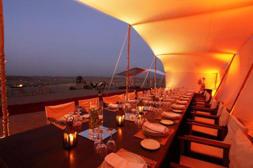 a long dining table in a tent with a view at CameLuxe Camp in Mhamid