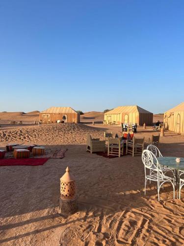 a desert with tents and a table and chairs in the sand at CameLuxe Camp in Mhamid