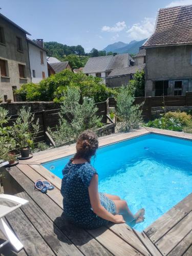 une femme assise sur une terrasse à côté d'une piscine dans l'établissement Chambres d'hôtes Les Chatougoulis, à Les Bordes-sur-Lez