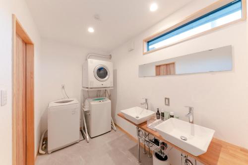 ein Badezimmer mit 2 Waschbecken und einer Waschmaschine in der Unterkunft 深々 books&stay シンシンブックスアンドステイ in Matsukawa
