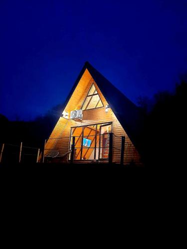 a wooden house with a lit up window at night at Casuta dintre nuci 