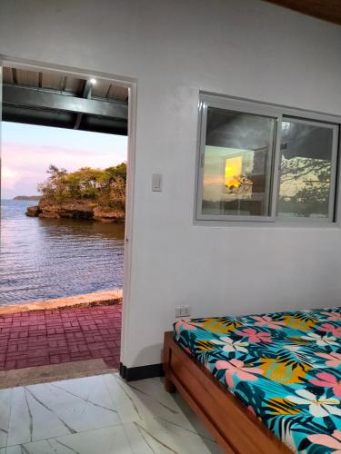 a bedroom with a bed and a view of the water at Bolo Beach Santorini nearby to Hundred Island in Alaminos