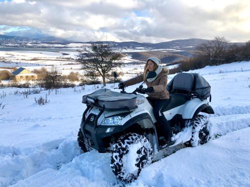 a woman riding a quad bike in the snow at Laguna Beach Club Bazaleti Lake in Dushetʼi