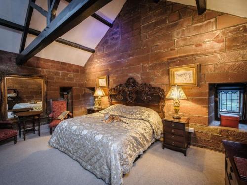 a bedroom with a large bed and a stone wall at Dalston Hall in Carlisle