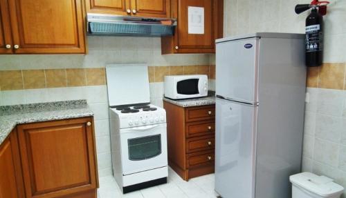 W kuchni znajduje się biała lodówka i kuchenka mikrofalowa. w obiekcie Al Massa Hotel Apartments 1 w mieście Al-Ajn