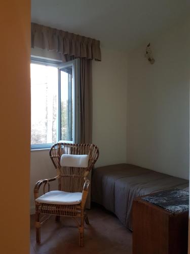 Un dormitorio con una cama y una silla y una ventana. en A casa di Samuele, en Squille