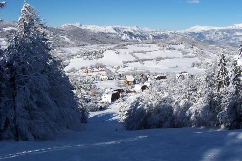 a village covered in snow with trees and mountains at Domaine de l'Adoux in Saint-Jean Montclar